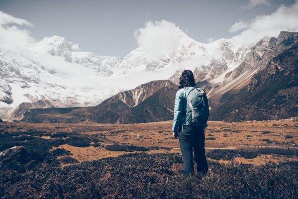 standing-young-woman-with-backpack-and-mountains-PB9ZHMG-min
